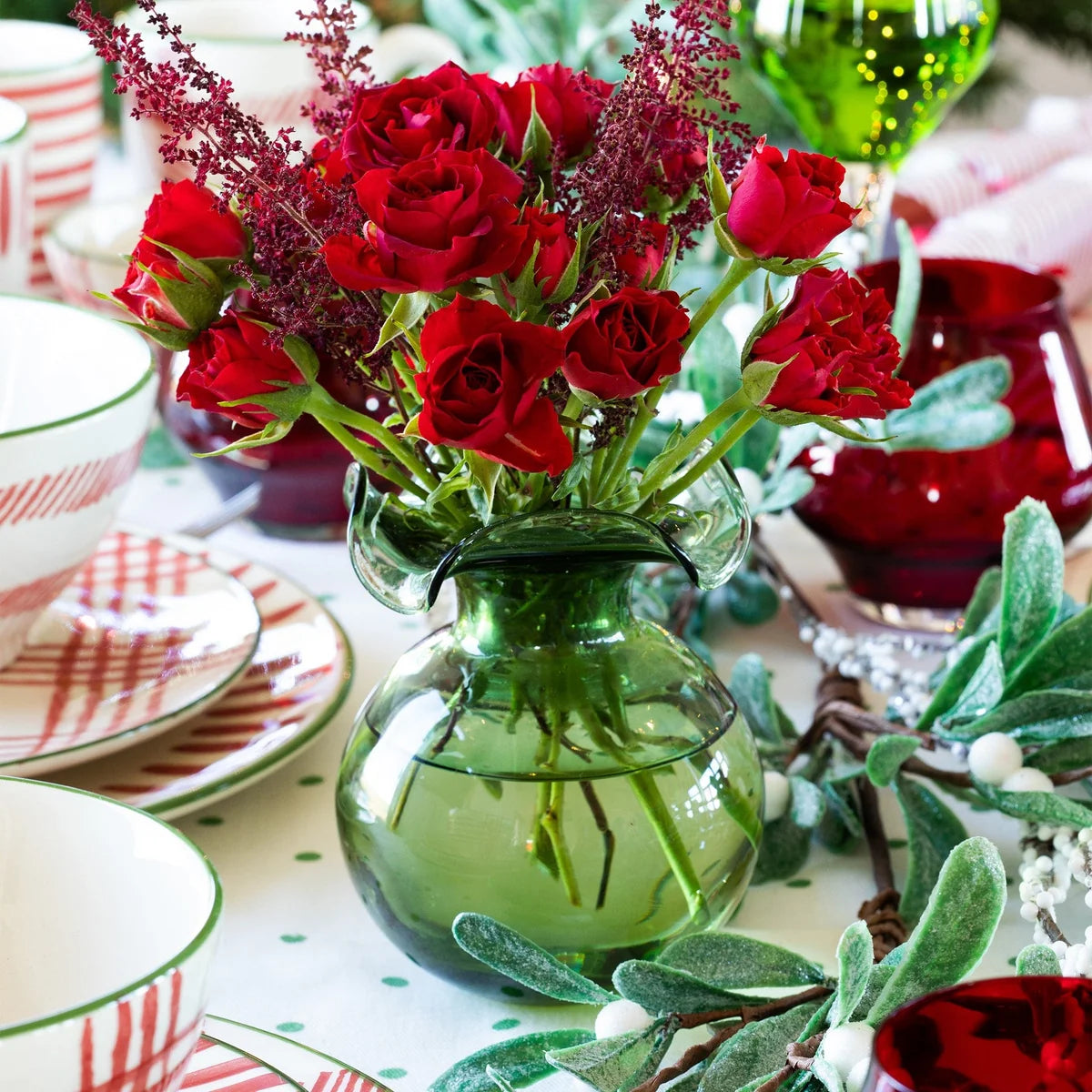 Green vase with red roses on a festive table setting