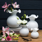 Set of white vases with flowers on a wooden surface