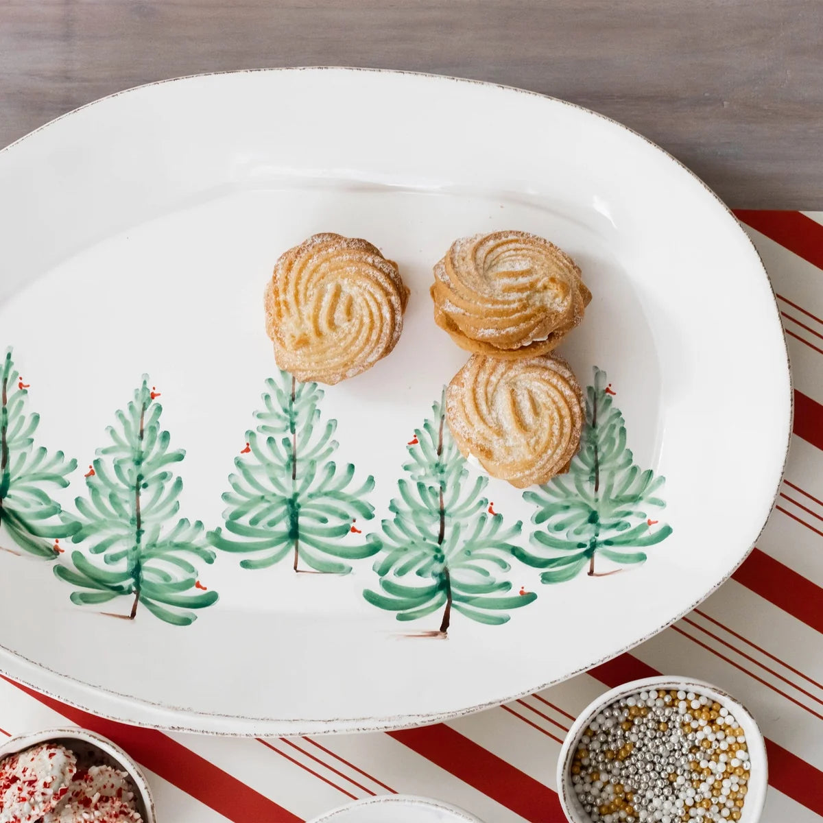 Decorative plate with Christmas tree design holding pastries on a striped tablecloth.