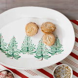 Decorative plate with Christmas tree design holding pastries on a striped tablecloth.