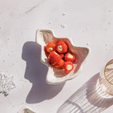 Decorative bowl with red apples on a textured white surface
